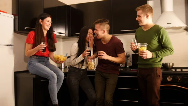 Cuatro jóvenes de pie en la cocina y hablando — Foto de Stock