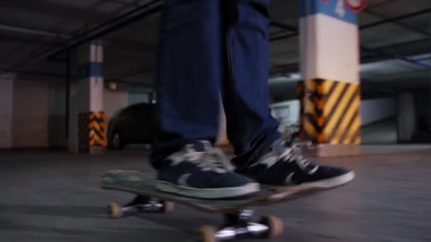 Ein junger Mann skateboardet auf seinem Brett in Militärfarben auf dem Parkplatz. Füße im Fokus. — Stockvideo