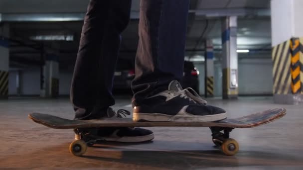 一个年轻的人在停车场的板子上滑板, 他的板子上有军品。侧视图 — 图库视频影像