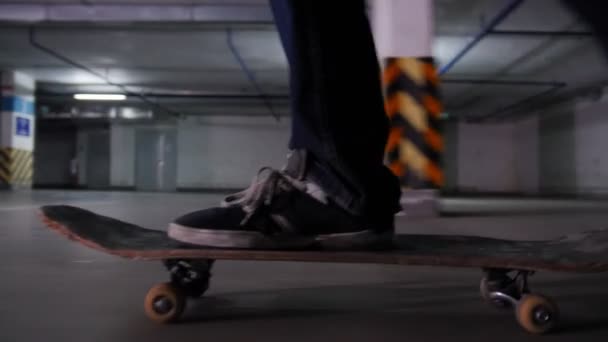 Młody człowiek skateboarding na jego pokładzie wojskowej kolory z dużą prędkością na parkingu. Widok z boku — Wideo stockowe