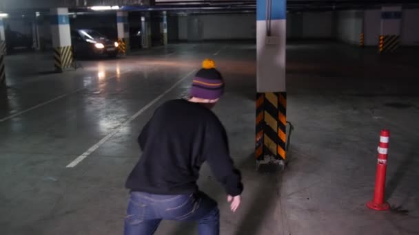 Młody człowiek, skateboarding na jego pokładzie z wojskowych kolory na parkingu. Na rolkach wokół przeszkód. Widok z tyłu — Wideo stockowe