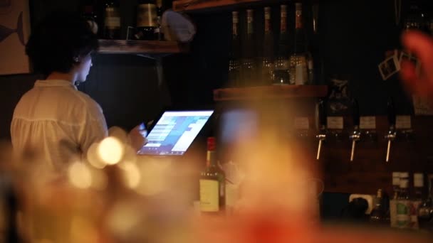 Een jonge vrouw ober in bar registreren de gastentafel — Stockvideo
