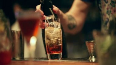 Barmen çalışıyor. Bir alkollü kokteyl cam karıştırma. Ekleme kabarcıklar, bir kaşık ile karıştırma ve hizmet bitirmek