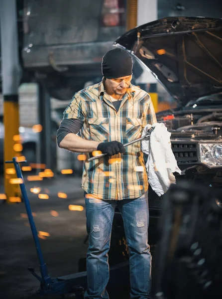 Servicio de coches. Hombre mecánico de pie junto al coche y limpia la herramienta. Chispas — Foto de Stock