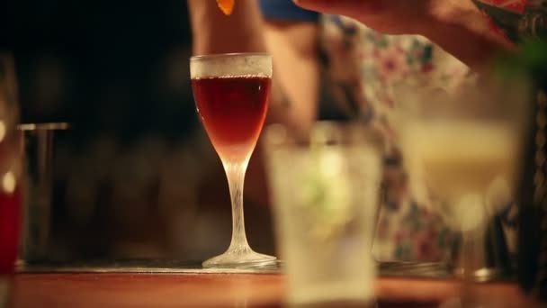 En bartender som dekorerar en alkoholhaltig drink i glas — Stockvideo