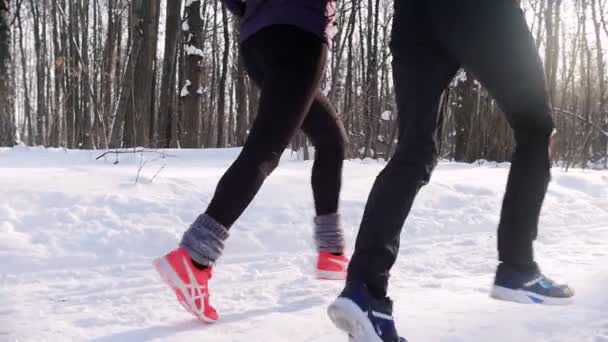 Zimní les. Mladý muž a žena běží na stezce v lese ráno. — Stock video