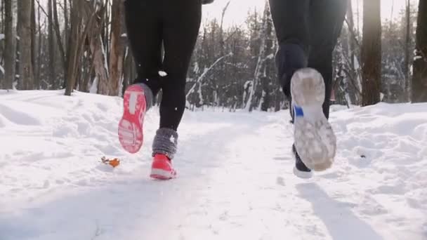 Giovane uomo e donna che corrono nella foresta invernale. Buongiorno. La neve vola fuori da sotto le suole — Video Stock