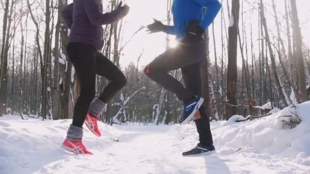 Молодой человек и женщина делают упражнения в зимнем парке утром. Бег на месте — стоковое видео