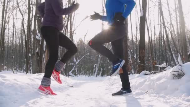 Fiatal férfi és nő gyakorolja a téli reggel parkban. Futás a helyszínen — Stock videók