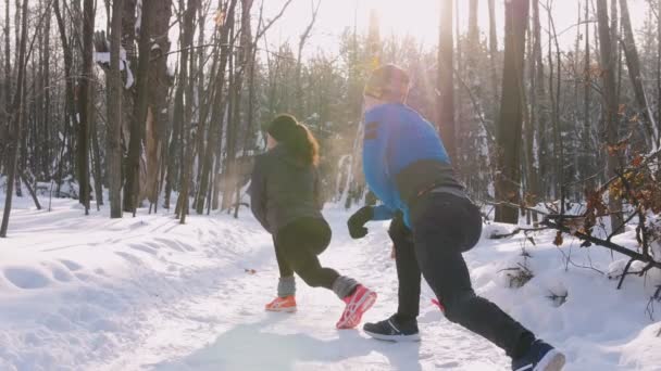 Νεαρός άνδρας και γυναίκα κάνει ασκήσεις στο πάρκο το πρωί χειμώνα. Ζέσταμα — Αρχείο Βίντεο