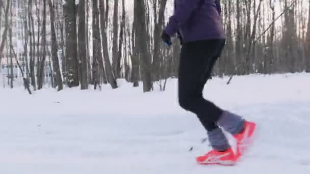 Νεαρός άνδρας και γυναίκα που τρέχει στο δάσος του χειμώνα. Νωρίς το πρωί. Πλάγια όψη — Αρχείο Βίντεο