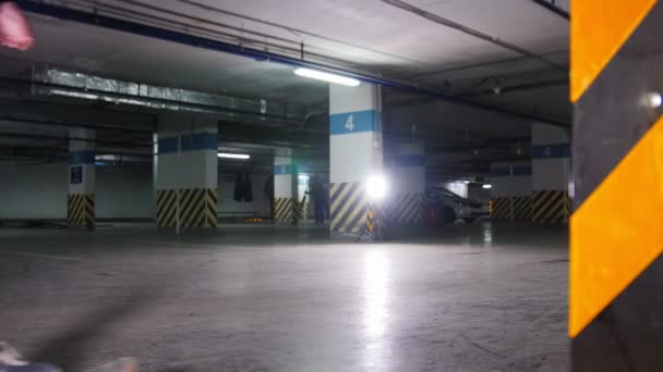 Entrenamiento de skate. Un joven patinando dentro del estacionamiento, se detiene y toma la tabla en la mano — Vídeos de Stock