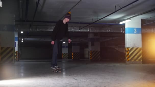 Estacionamento subterrâneo. Um jovem a andar de skate. Fazendo um giro — Vídeo de Stock