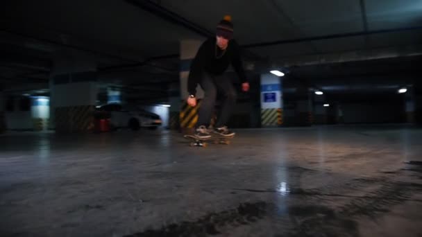 Підземний паркінг. Молодий чоловік катається на скейтборді. Практикуючи олію — стокове відео