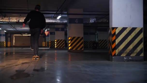 Підземний паркінг. Молодий чоловік практикує навички скейтбордингу — стокове відео