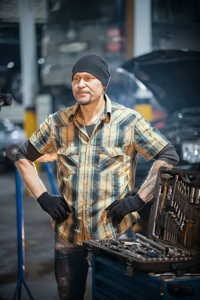 Servicio de reparación de coches. Brutal mecánico se para sosteniendo una llave inglesa — Foto de Stock