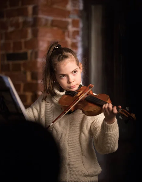 Une petite belle fille en pull jouant du violon — Photo