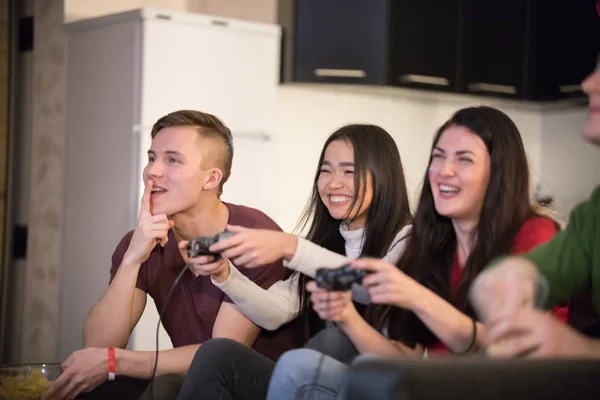 Company of young friends spending time together. Two young woman playing game using a joystick. Excitement — Stock Photo, Image