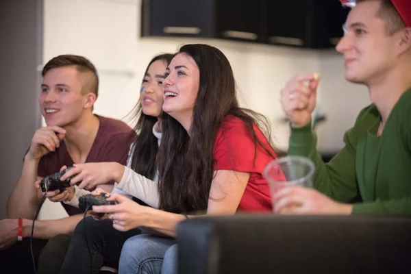 Compañía de jóvenes amigos divirtiéndose juntos. Dos mujeres jóvenes jugando usando un joystick. Emoción. — Foto de Stock