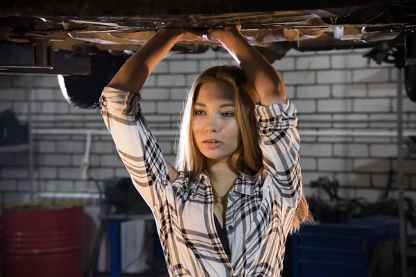 Młoda sexy kobieta mechanik stojąc pod samochód w usługi naprawy samochodów — Zdjęcie stockowe