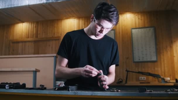 Shooting gallery. A young man preparing the gun for shooting. Charging the gun with a bullets — Stock Video