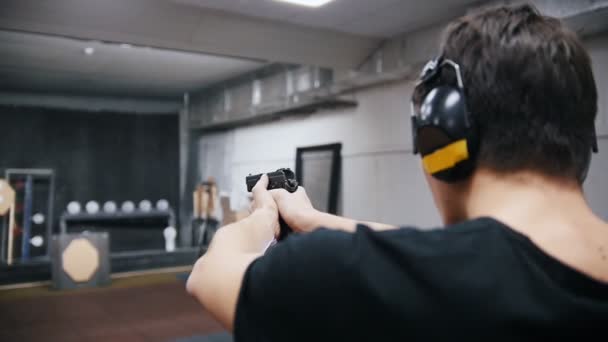 シューティング ギャラリー シャツ 銃器を撮影の若い男 背面図 — ストック動画