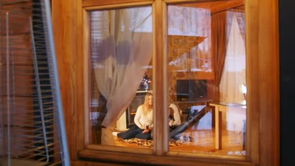 Mladá rodina sedí na podlaze v útulném domě. Pohled z okna — Stock video