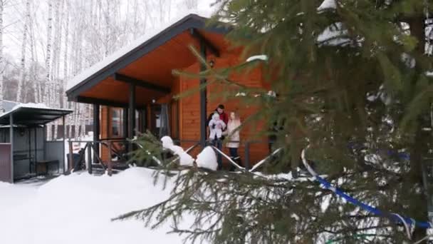 Молодая семья стоит на веранде красивого дома — стоковое видео