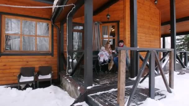 Jeune famille buvant des boissons chaudes sur la véranda d'une belle maison — Video