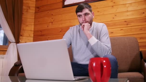 Ένας προβληματισμένος άνθρωπος ανεξάρτητος εργαζόμενος κάθεται από το φορητό υπολογιστή — Αρχείο Βίντεο