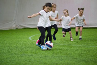 Çocuklar kapalı futbol oynuyor. Sahada çalışan çocuklar. Küçük bir çocuk topa hazırdır