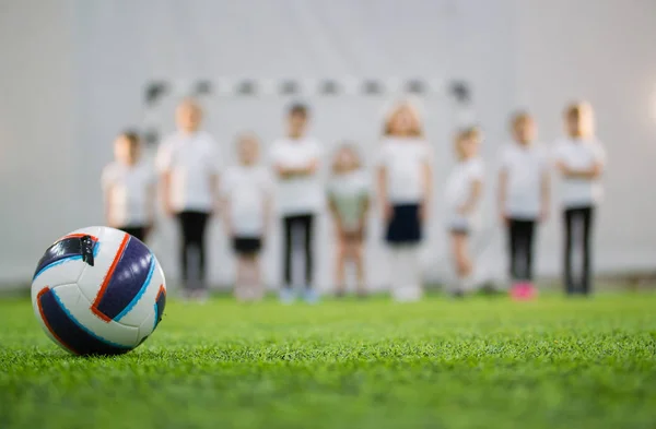 Kinder stehen in der Schlange auf einem Fußballplatz. Fußball im Vordergrund — Stockfoto