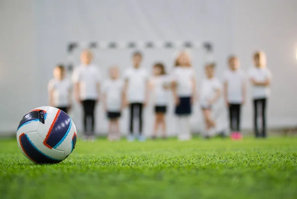 Kinder stehen in der Schlange auf einem Fußballplatz. Fußball im Vordergrund — Stockfoto