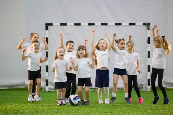 Miúdos a jogar futebol em casa. Equipa de futebol infantil. Mãos para cima e pulando — Fotografia de Stock