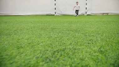 Kapalı futbol arena. Küçük çocuk topu tek başına yol açar.