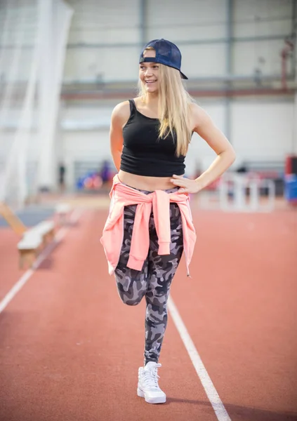 Jovem mulher atlética sorridente esticando as pernas — Fotografia de Stock
