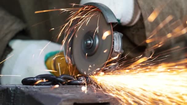 De werknemer van een man gesneden de keten met een grinder — Stockvideo