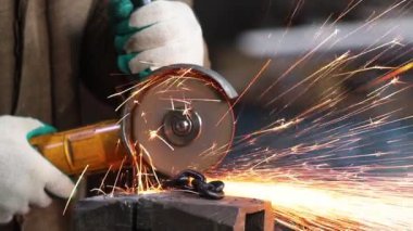 Bir adam işçi siyah bir zincir bir öğütücü ile yangın sparkles kesmek