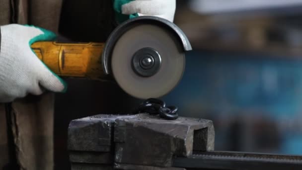 A man worker cut a black chain with a grinder — Stock Video