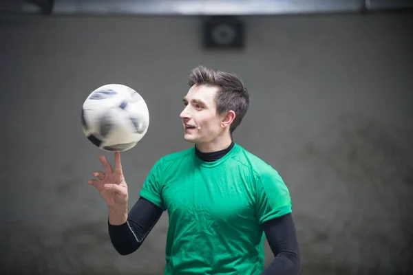 Soccer player training his skills with a ball. Spinning the ball on a finger