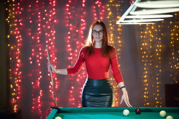 Una donna rossiccia in piedi nel club di biliardo che tiene una stecca — Foto Stock