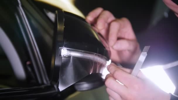 Ένας άνθρωπος καταργεί την υπέρβαση από έναν cuted προστατευτικό φάκελο για ένα αυτοκίνητο rearview καθρέφτη — Αρχείο Βίντεο