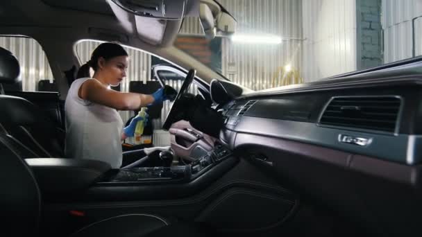 Μια νεαρή γυναίκα καθαρισμού τιμόνι του αυτοκινήτου — Αρχείο Βίντεο