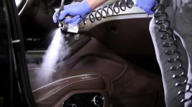 Araba Servisi. Bir arabada deri koltukta Temizlik maddesi püskürtme