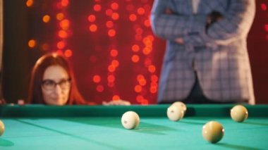 Bilardo oynarken bir çift. Bir kadın hedefleyen ve hit top