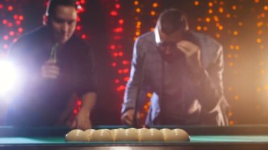 İki adam Bilardo masası tarafından ayakta tartışmak oyun taktikleri ve adamlardan biri topa vurmak