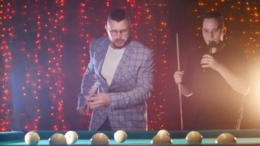 Bilardo masası tarafından ayakta ve oynarken bira içme iki adam. Sakallı adam iyi bir hamle yaptı