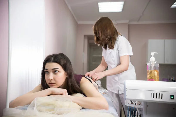 Cosmetología clínica de belleza. mujer joven que toma mioestimulación y médico que prepara el procedimiento en el consultorio de nutricionistas — Foto de Stock