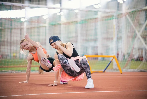 Two young beautiful women with blonde hair doing cardio exercises and breathing hard in the sports hall — Stock Photo, Image
