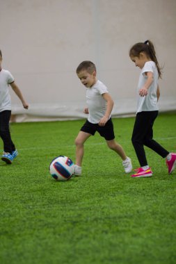 Küçük çocuklar futbol oynarken sahada topu tekmeleme